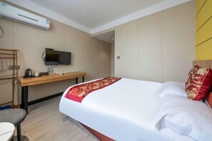 Ein Hotelzimmer mit Bett, Schreibtisch, Fernseher und Klimaanlage.