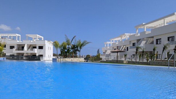 Un hotel moderno con una piscina grande, arquitectura blanca y palmeras.