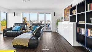A modern living room with a black leather sofa, a white cabinet, and a bookshelf.