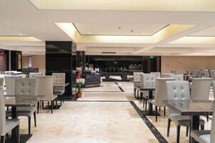 A modern hotel lobby with a central bar area, seating arrangements, and a marble floor.