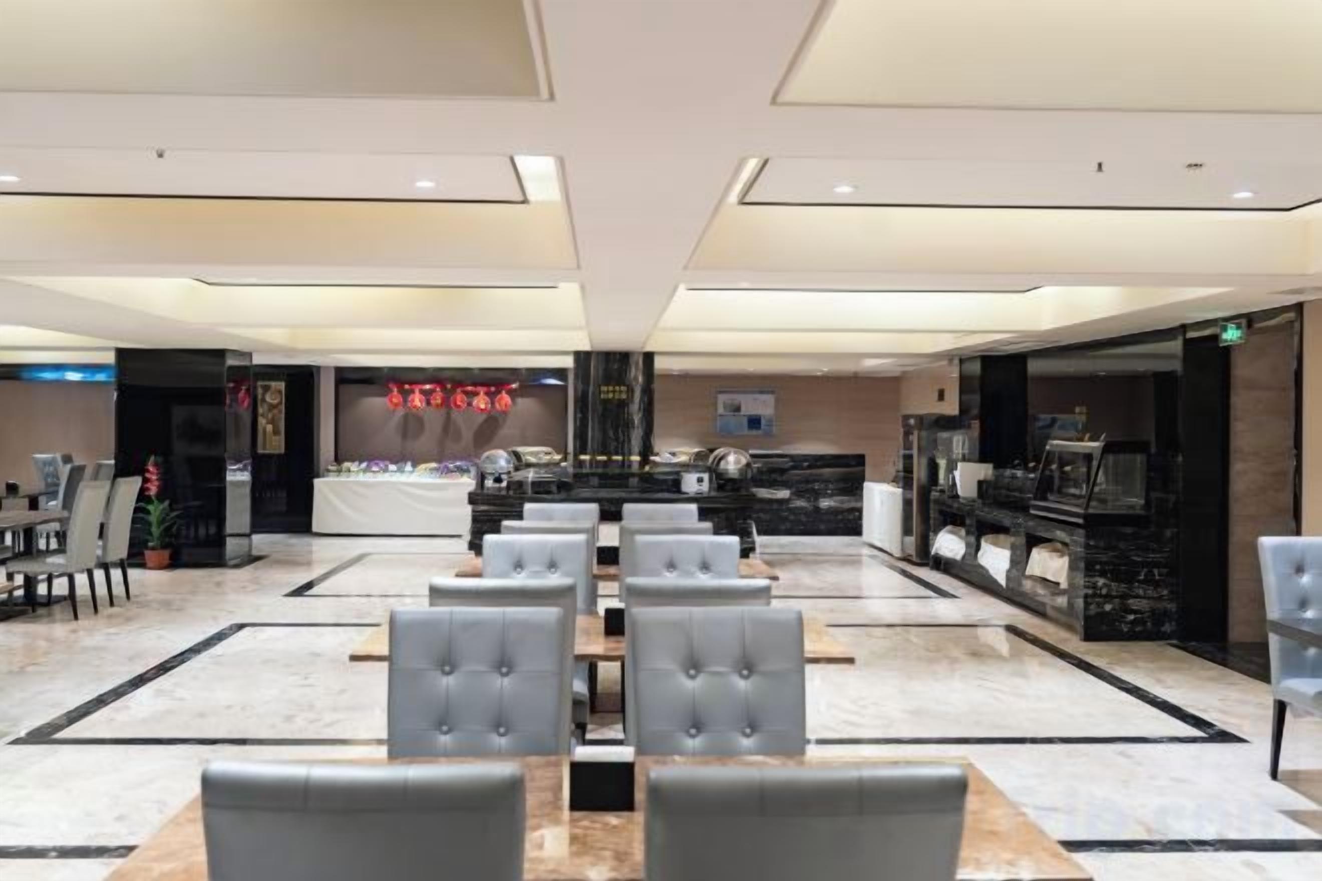 Un amplio hall de hotel con piso de mármol, una recepción y un área de estar con sillas.
