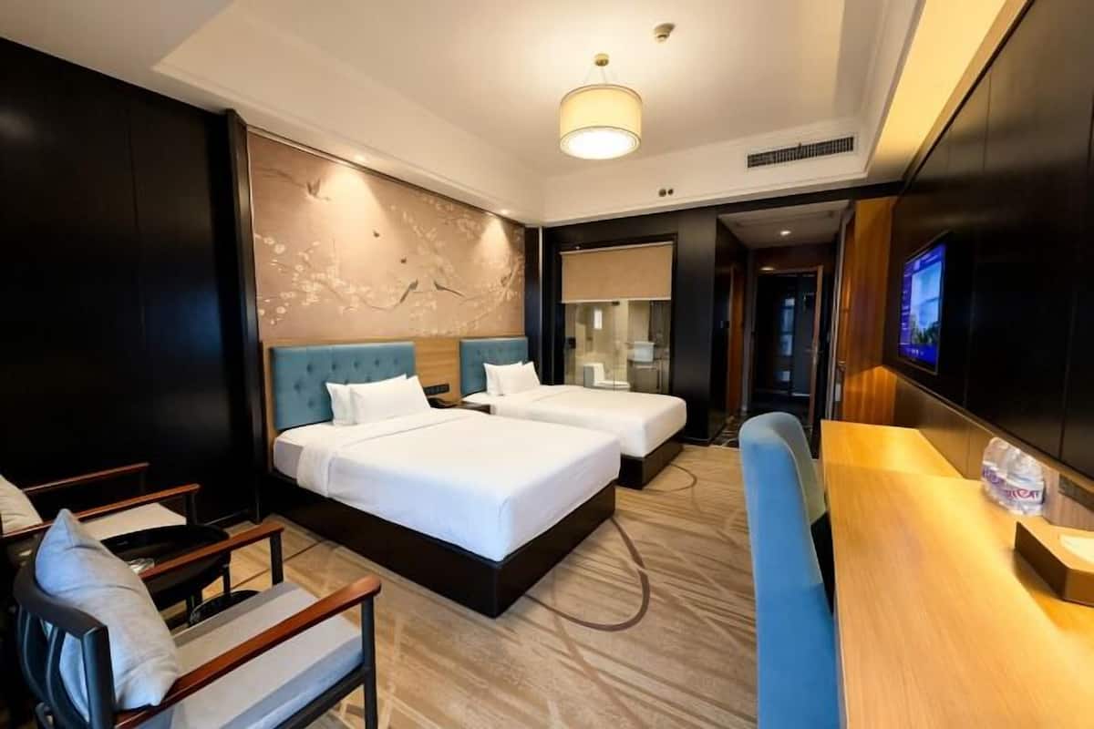 Une chambre d’hôtel avec deux lits, un bureau, une télévision et un coin salon.
