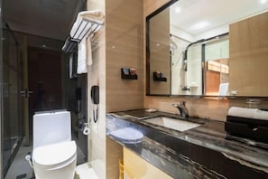Un baño moderno con lavamanos de mármol, un espejo grande y un inodoro.
