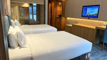 A hotel room with two beds, a TV, a mirror, and a wardrobe.