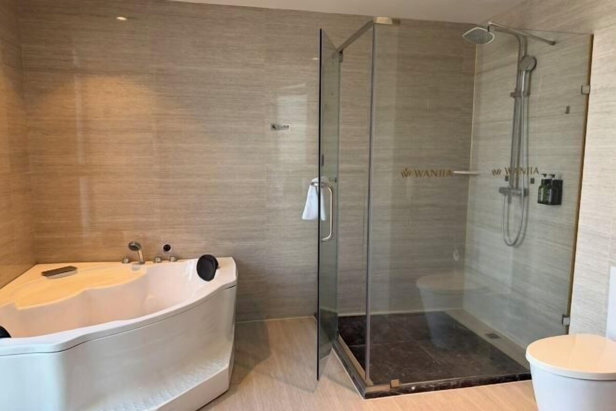 Un baño moderno con ducha envuelta en vidrio, una bañera independiente y un inodoro.