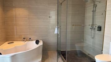 A modern bathroom with a glass-enclosed shower, a freestanding bathtub, and a toilet.