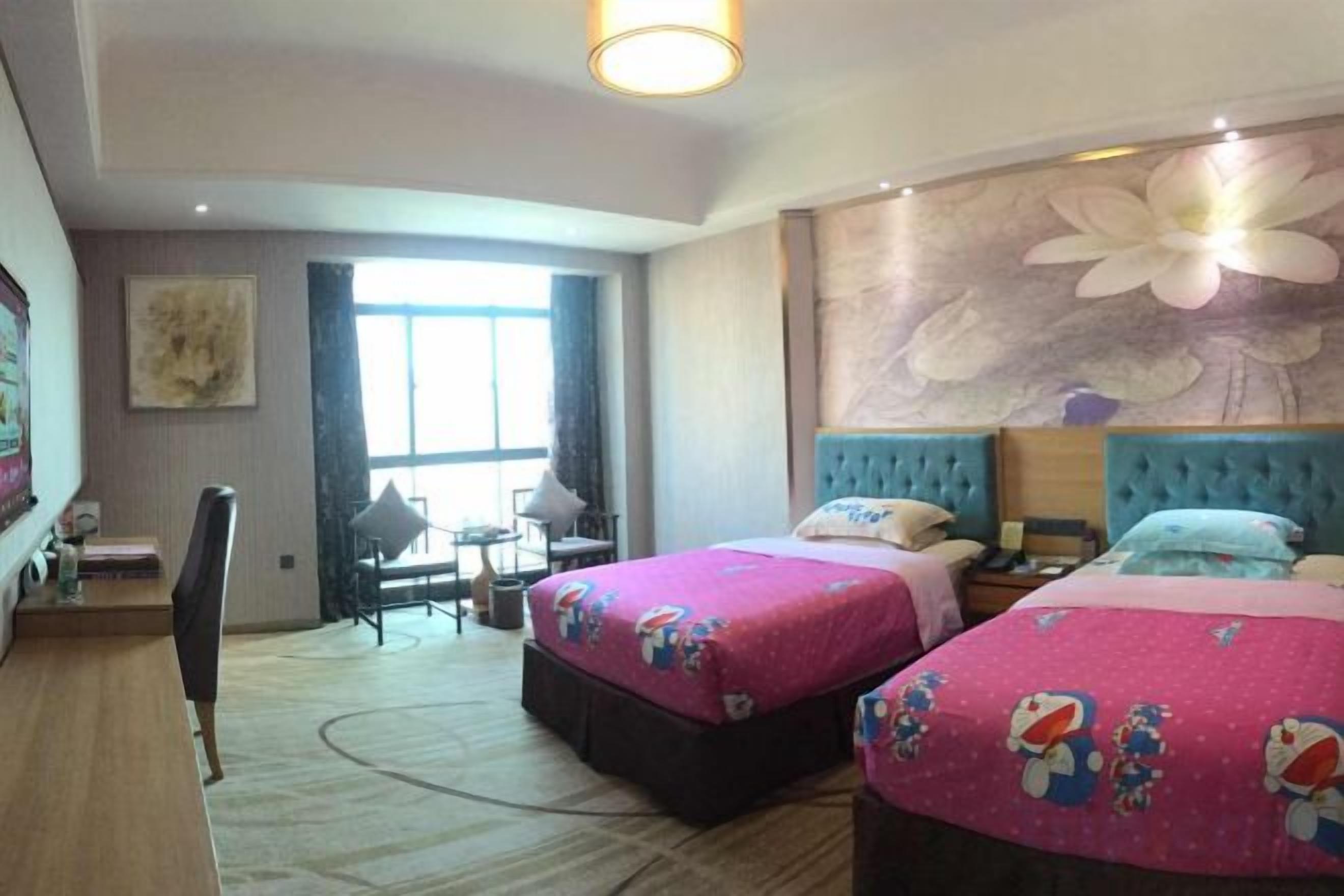 A hotel room with two beds, a desk, a chair, and a large window.