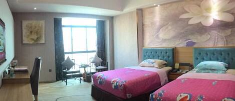 A hotel room with two beds, a desk, a chair, and a large window.