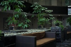A lobby with seating areas, potted plants, and a water feature.