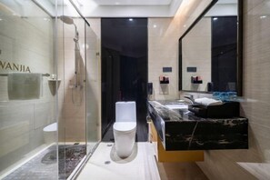 Un baño moderno con cabina de ducha de vidrio, inodoro blanco y encimera de mármol.
