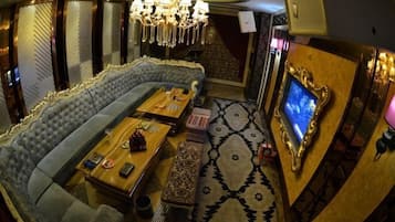 A luxurious room with a large, tufted sofa, a wooden coffee table, and a television on the wall.