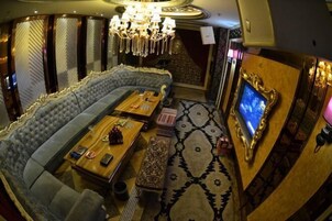 Una habitación lujosa con un sofá grande y capitonado, una mesa de centro de madera y un televisor en la pared.