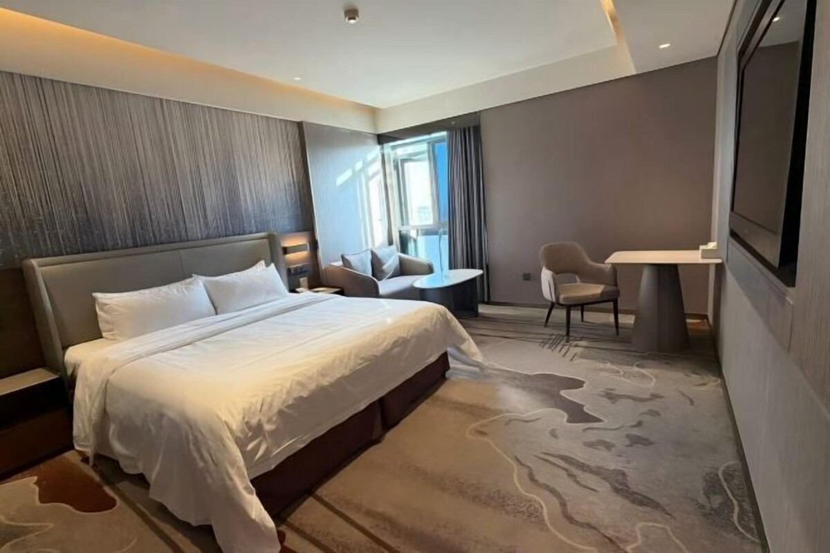 Una habitación de hotel moderna con una cama grande, un escritorio y una silla.