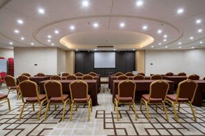 A conference room with round tables and chairs, a projector screen, and a carpeted floor. - Wanjia International Hotel (Nan'an)