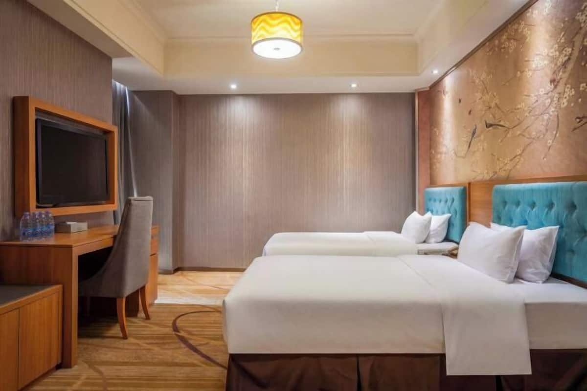Une chambre d’hôtel avec un grand lit, un bureau avec une chaise, une télévision et un mur décoratif.