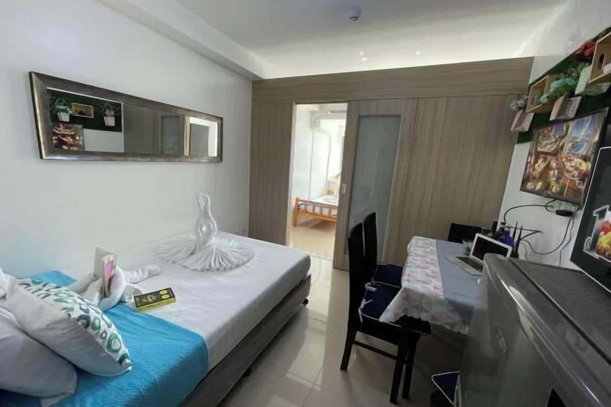 Ein Hotelzimmer mit Bett, Schreibtisch, Stuhl, Spiegel und Fernseher.