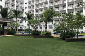 Une cour d’hôtel avec une piscine, des palmiers et un immeuble à plusieurs étages doté de balcons.