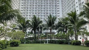 Un hotel moderno de gran altura, rodeado de abundante vegetación y palmeras.
