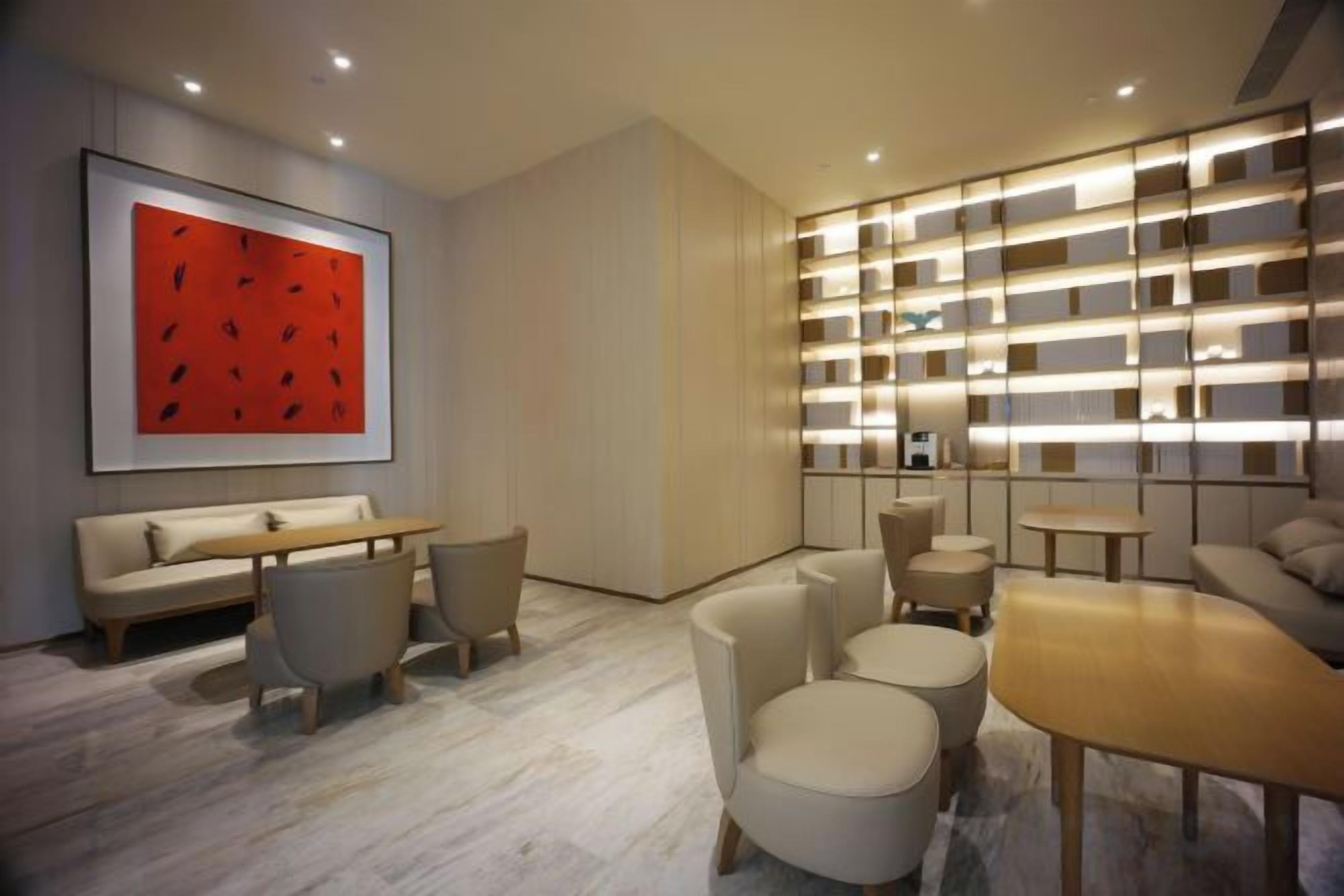 A modern interior with a sofa, chairs, a table, and a bookshelf.