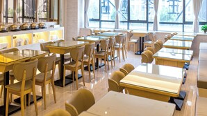 A modern restaurant with glass tables, wooden chairs, and a view of buildings through large windows. - Ji Hotel (Jiaxing)