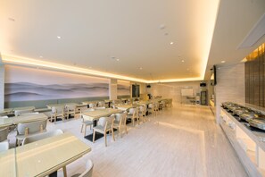 A modern dining area with tables and chairs, a buffet line, and a mural on the wall. - Ji Hotel (Jiaxing)