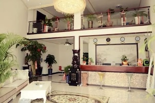Un salón amplio con techo alto, un balcón con plantas en macetas y un ventanal grande.