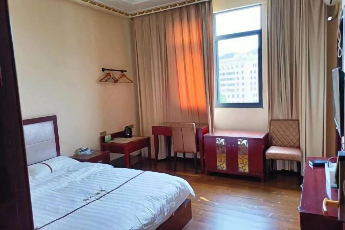 Una habitación de hotel con cama, escritorio, silla y armario.