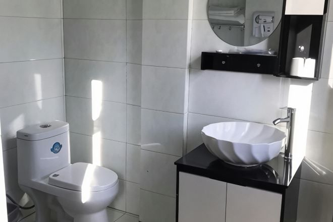 A modern bathroom with a white toilet, a black countertop, and a white sink.