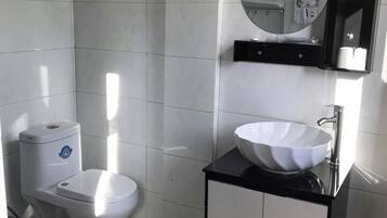 A modern bathroom with a white toilet, a black countertop, and a white sink.