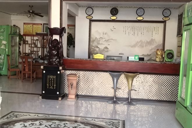 A reception area with a counter, chairs, a decorative statue, and a wall with a framed text.