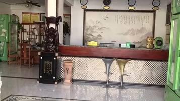 A reception area with a counter, chairs, a decorative statue, and a wall with a framed text.