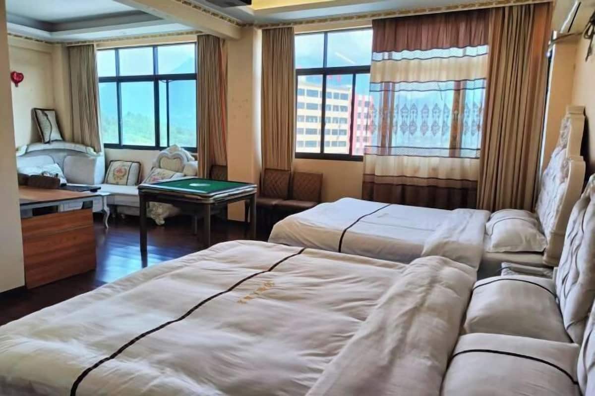 Habitación de hotel con dos camas, un escritorio, una silla, una mesa de billar y ventanas amplias con cortinas.