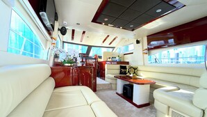 Interni di uno yacht con zona pranzo, cucina e salottino vista città.