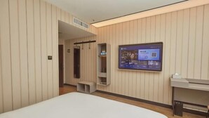 Une chambre d’hôtel moderne équipée d’un grand lit, d’un téléviseur fixé au mur, d’un bureau et d’une armoire.