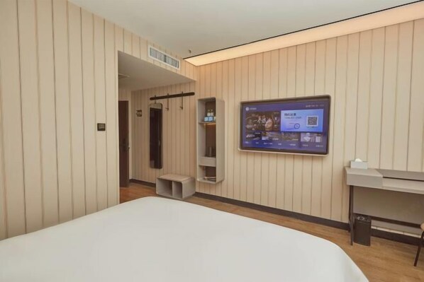 Une chambre d’hôtel moderne équipée d’un grand lit, d’un téléviseur fixé au mur, d’un bureau et d’une armoire.