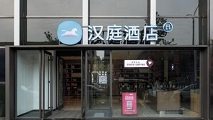 L’entrée d’un hôtel, avec une enseigne indiquant « 汉庭酒店 » et une enseigne « Costa Coffee » visible à l’intérieur.