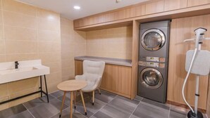 Une petite salle de bain comprenant un lavabo, une chaise et un lave-linge.
