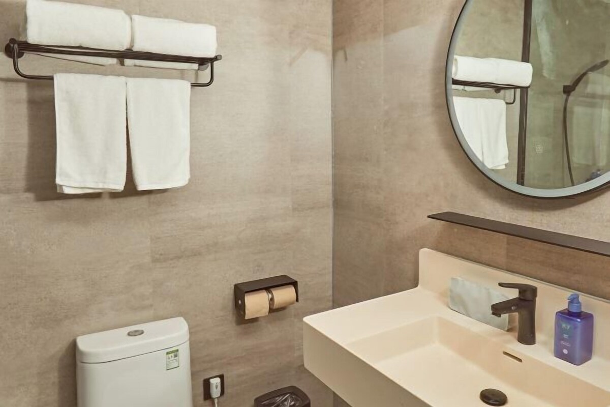 Une salle de bain équipée d’un WC, d’un lavabo, d’un miroir, d’un porte-serviettes et d’un distributeur de serviettes.