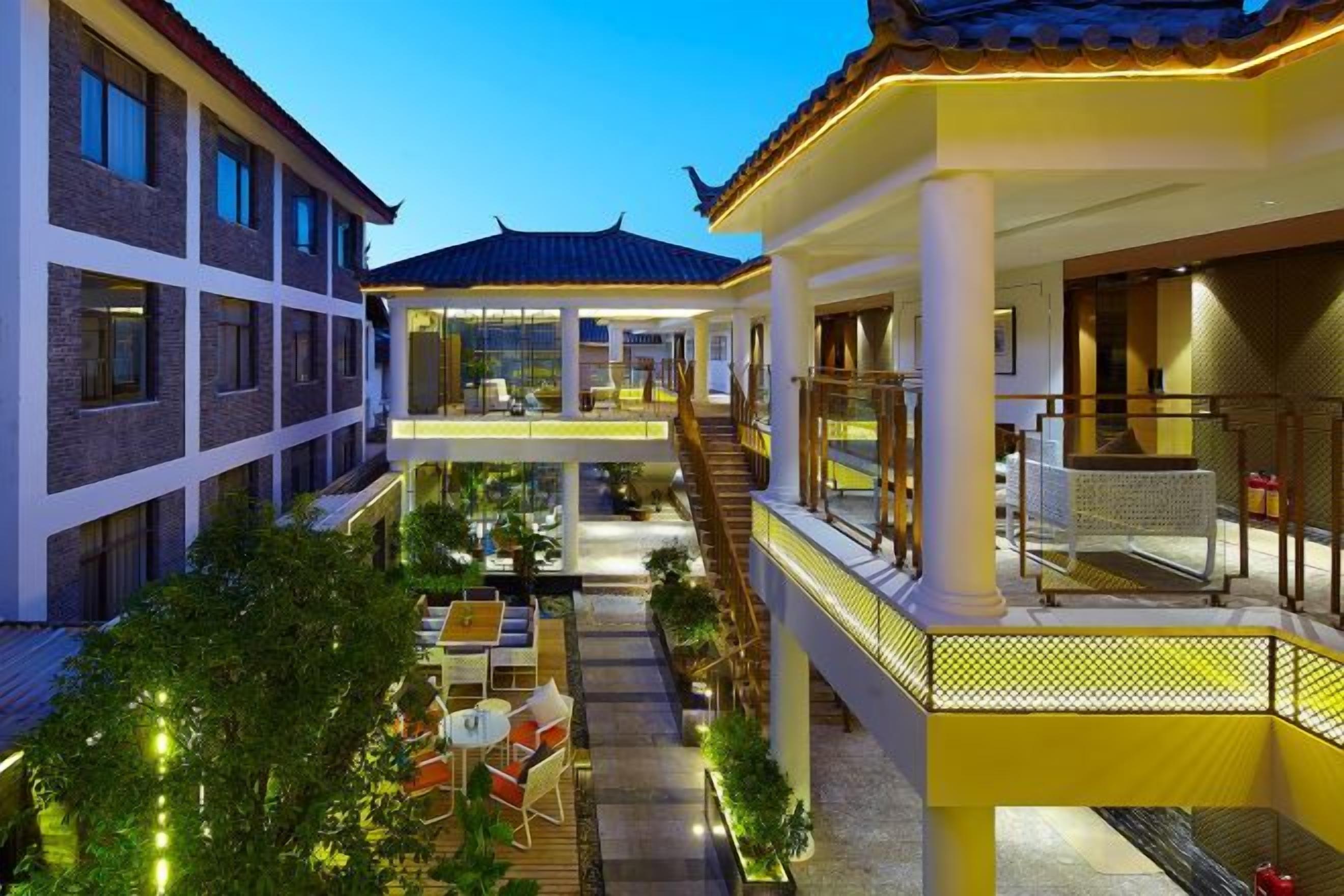 A hotel courtyard with outdoor seating, a covered area, and a staircase leading to an upper level.