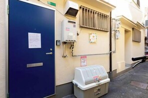 Una puerta azul, un equipo de aire acondicionado, un dispensador de agua y un extintor en una pared de edificio.