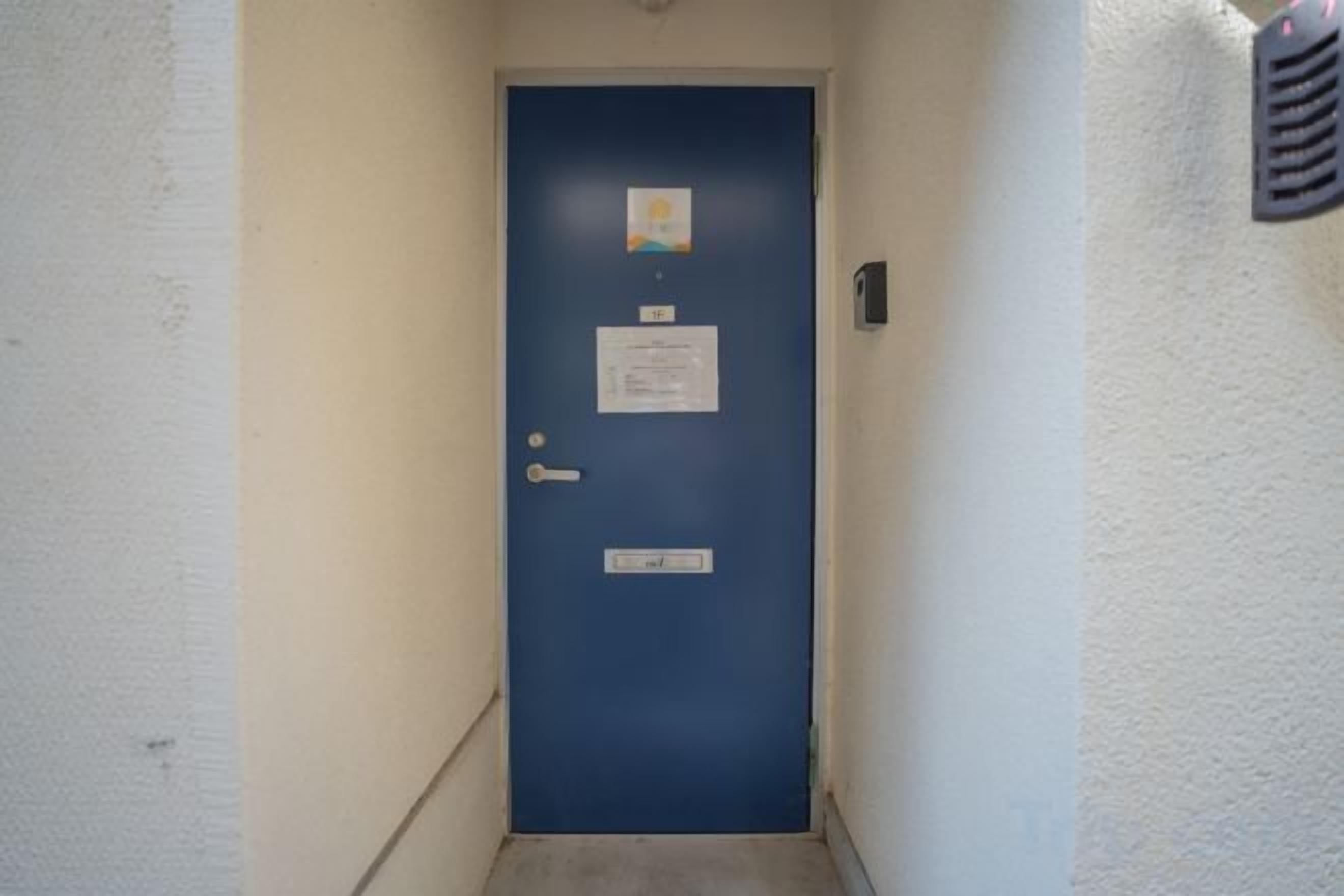 A blue door with a nameplate, a keycard reader, and a small sign above it.