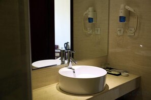 A bathroom with a round white sink, a mirror, and two wall-mounted soap dispensers. - Yixin Hotel (Xinfeng)
