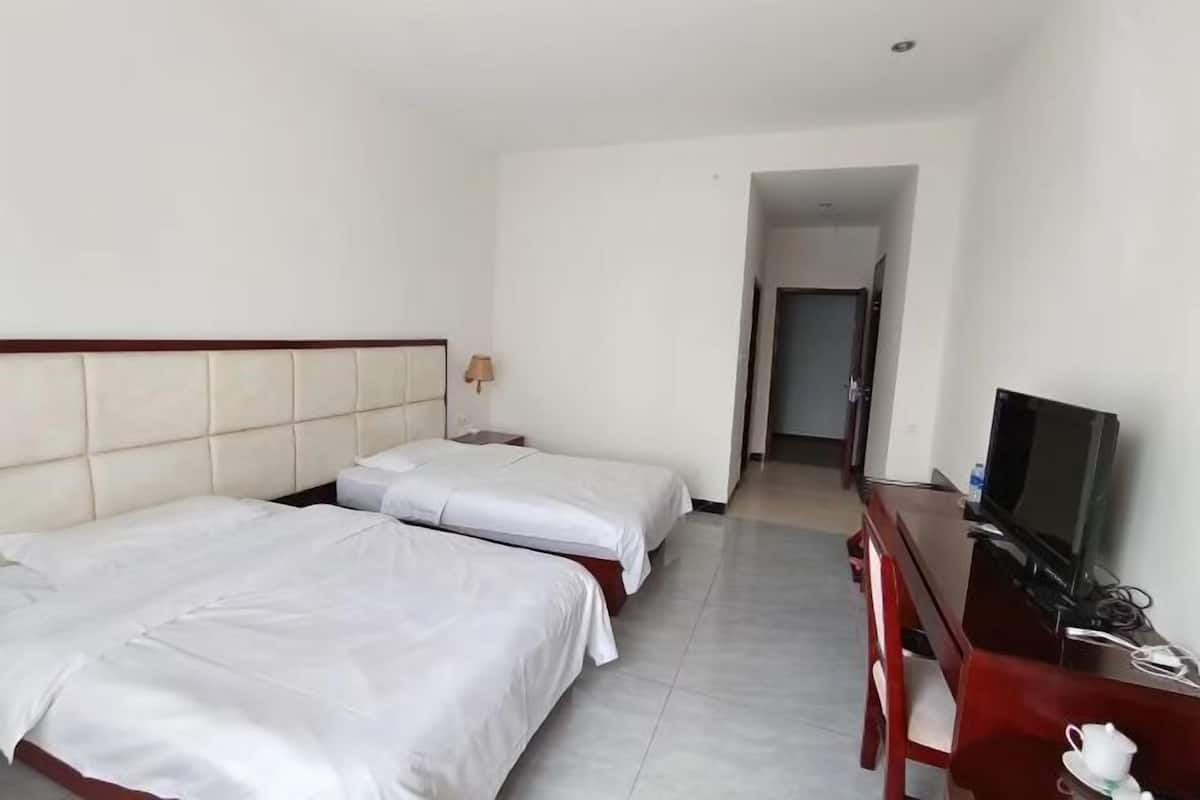 Une chambre d’hôtel avec deux lits, une télévision, un bureau et une lampe.