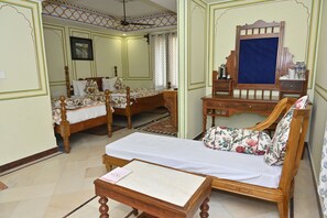 A traditional room with two wooden beds, a wooden sofa, a small table, and a mirror. - Hotel Rime Vista (Jaipur)