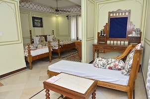 A traditional room with two wooden beds, a wooden sofa, a small table, and a mirror.
