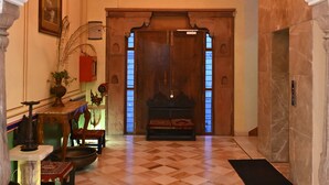 A hallway with a checkered floor, a wooden door, and a decorative ceiling. - Hotel Rime Vista (Jaipur)