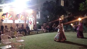 An outdoor event with people in traditional attire, a stage with colorful decorations, and a building in the background. - Hotel Rime Vista (Jaipur)
