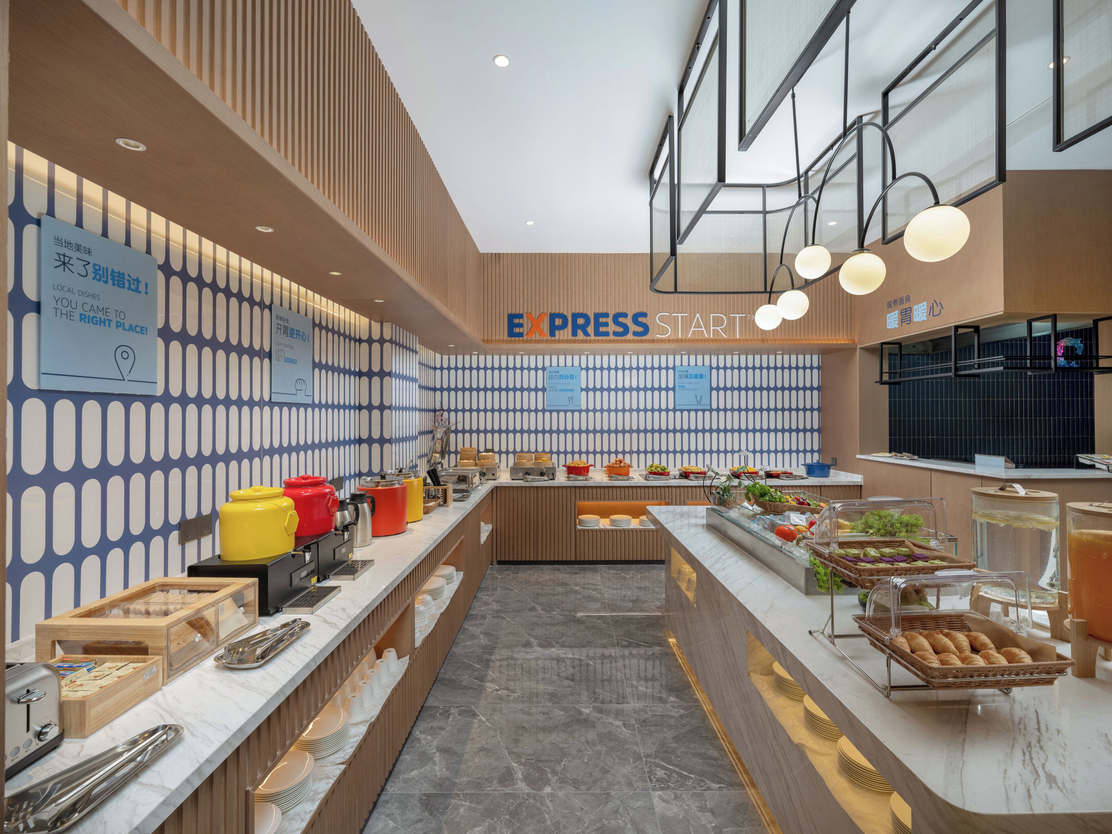 Un área de desayuno moderna con un sistema tipo bufé, que incluye diferentes alimentos y utensilios.