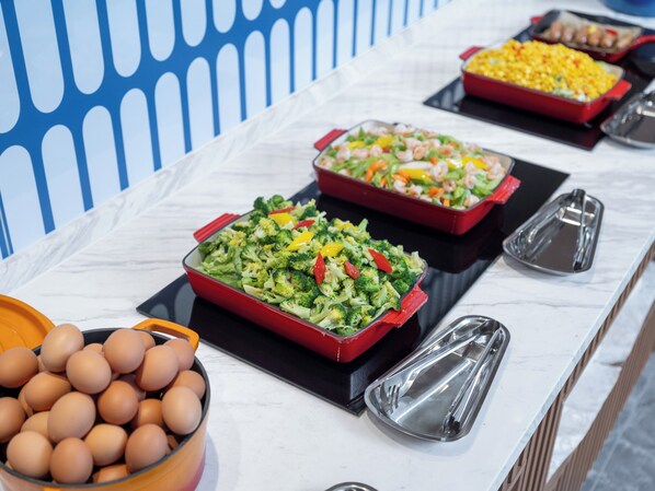 Una mesa de buffet con diversos platos, incluyendo un bol de huevos y múltiples bandejas de comida.