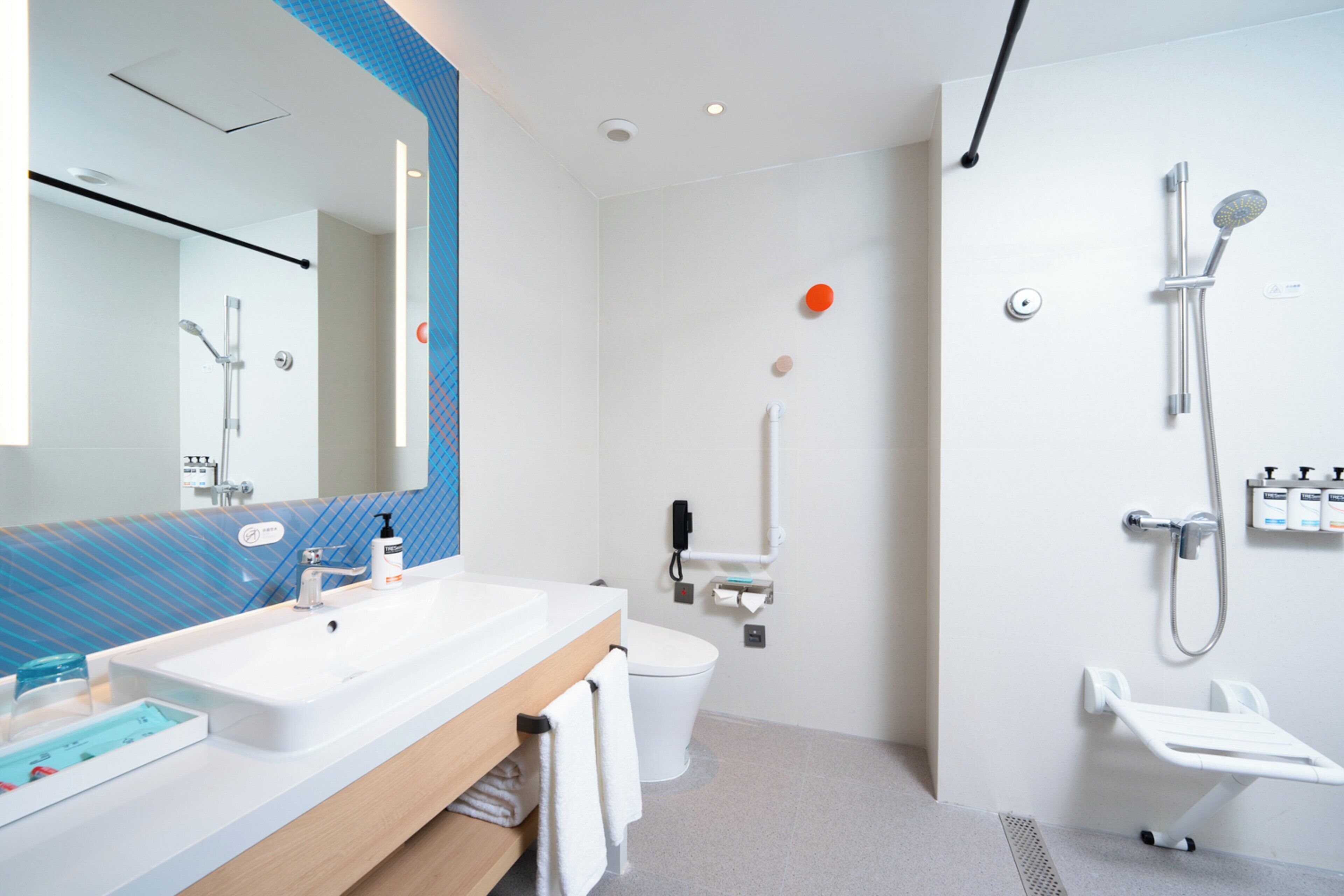 A modern bathroom with a white sink, mirror, and toilet, a shower area, and a towel rack.